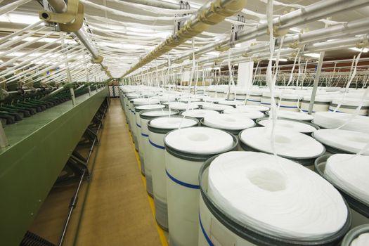 Rolls of fabric and machinery in spinning factory 