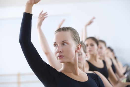 Young women with arms raised at the barre