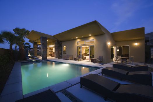 Lit swimming pool and house exterior at night