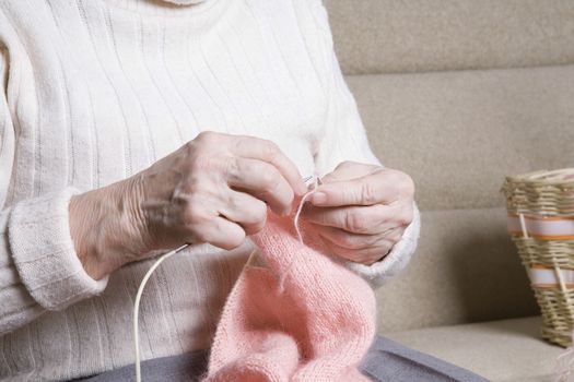 Elderly woman sits knitting