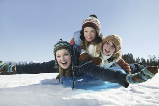 Three teenage girls lying on a sledge