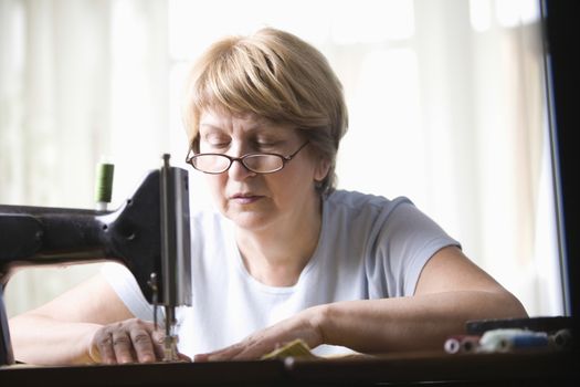 Mature woman works at sewing machine