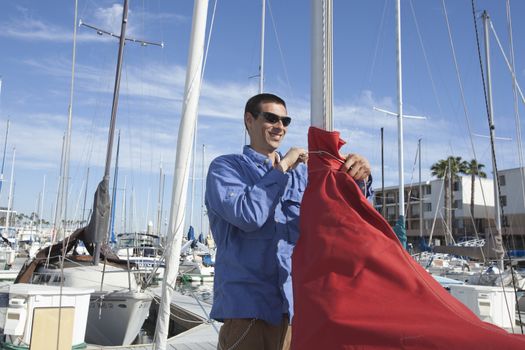 Young man securing sail of boat