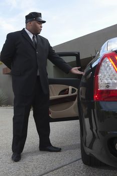 Chauffeur extends hand to client in  luxury vehicle