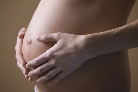 Pregnant woman stands with hands on stomach