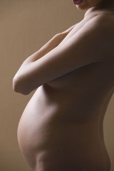 Pregnant woman stands with arm  across her chest