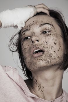 Young woman with bandage and muddy face