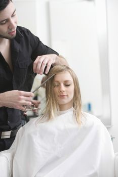 Man cutting a young womans hair in the hairdressers