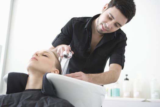 Man washing customers hair in the hairdressers
