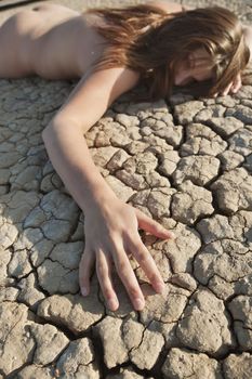 Close-up of a naked woman lying on cracked land