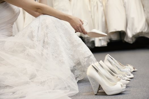 Low section of woman sitting with variety of footwear in bridal boutique