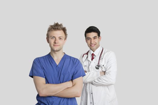 Portrait of male nurse and doctor standing with arms crossed over gray background