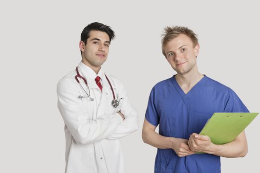 Portrait of doctor standing with coworker over light gray background