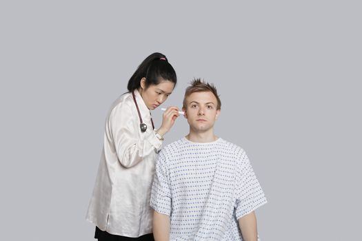 Doctor examining patient's ear with flashlight