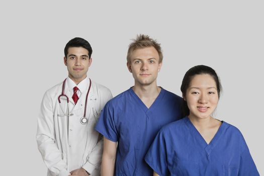 Portrait of confident multi ethnic medical team standing over gray background