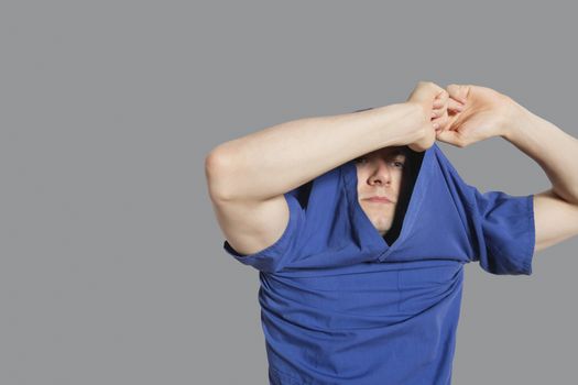 Young man removing t-shirt over colored background