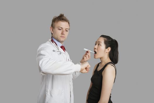 Doctor checking temperature of female patient