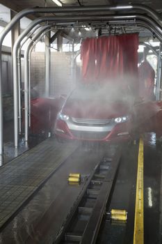 Vehicle on conveyor belt moving through car wash process
