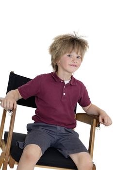 School boy sitting on director's chair over white background