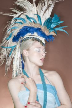 Beautiful young woman wearing feather headgear with eyes closed