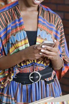 Midsection of woman in traditional African print attire using cell phone