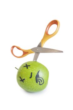 Granny smith apple murdered by scissor over white background