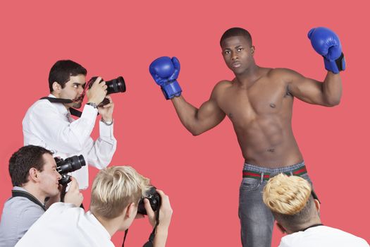 Paparazzi taking photographs of male boxer over red background