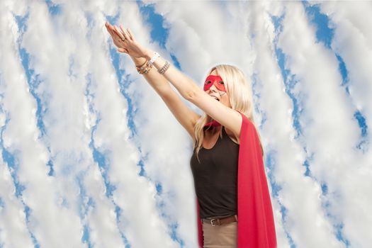 Young woman in superhero outfit taking a leap in the air against cloudy sky