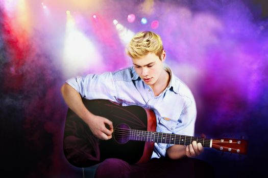 Young Caucasian man playing guitar in concert