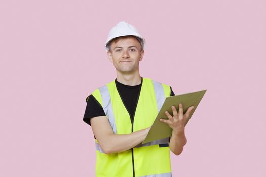 Portrait of a male construction worker with clipboard over pink background
