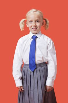 Portrait of a happy young girl in school uniform over orange background