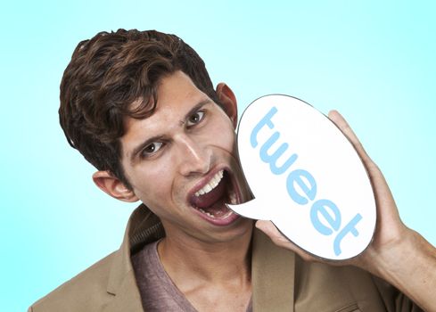 Portrait of young man holding tweet word bubble against white background