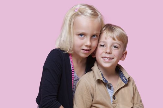 Portrait of young girl with happy brother over pink background