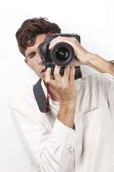 Young man taking photograph with vintage camera against white background