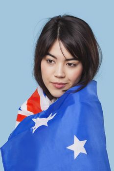 Patriotic young woman wrapped in Australian flag over blue background