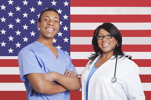 Portrait of confident mixed race male and female surgeons over American flag
