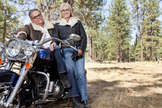 Senior couple lean on motorcycle in forest
