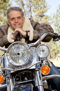 Senior man leaning on motorcycle handlebars
