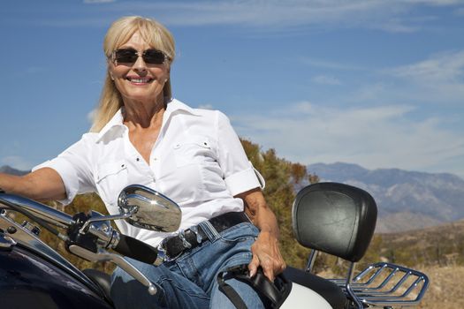 Senior woman sitting on motorcycle on desert road