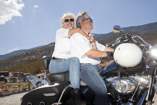 Senior couple riding a motorcycle together in a rural landscape