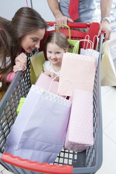 Close-up of young daughter in trolley being pushed by father and mother