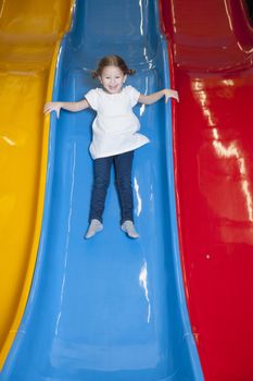 Young girl slides down colorful slide