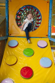 Young girl climbing down ramp in soft play centre
