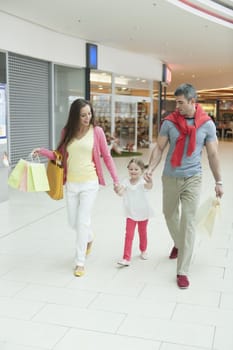 Young girl holding parents hands in shopping mall