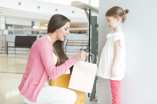 Mother giving daughter paper shopping bag