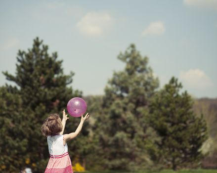 Young girl catching purple ball in park