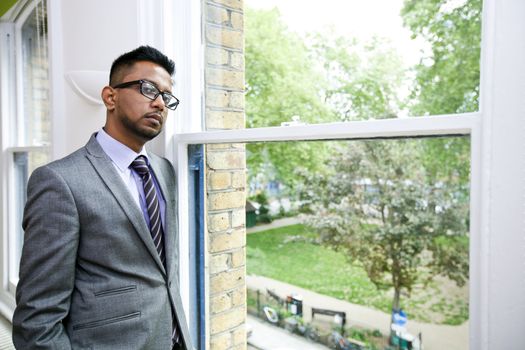 Portrait of Indian Businessman wearing glasses standing by the window