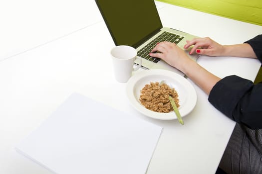 Close up of womans hands typing on laptop with mug in foreground