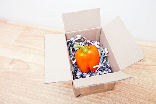 Orange bell pepper wrapped up in a box