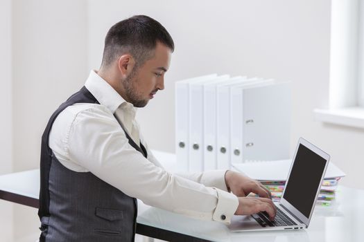 Young businessman using at laptop at desk